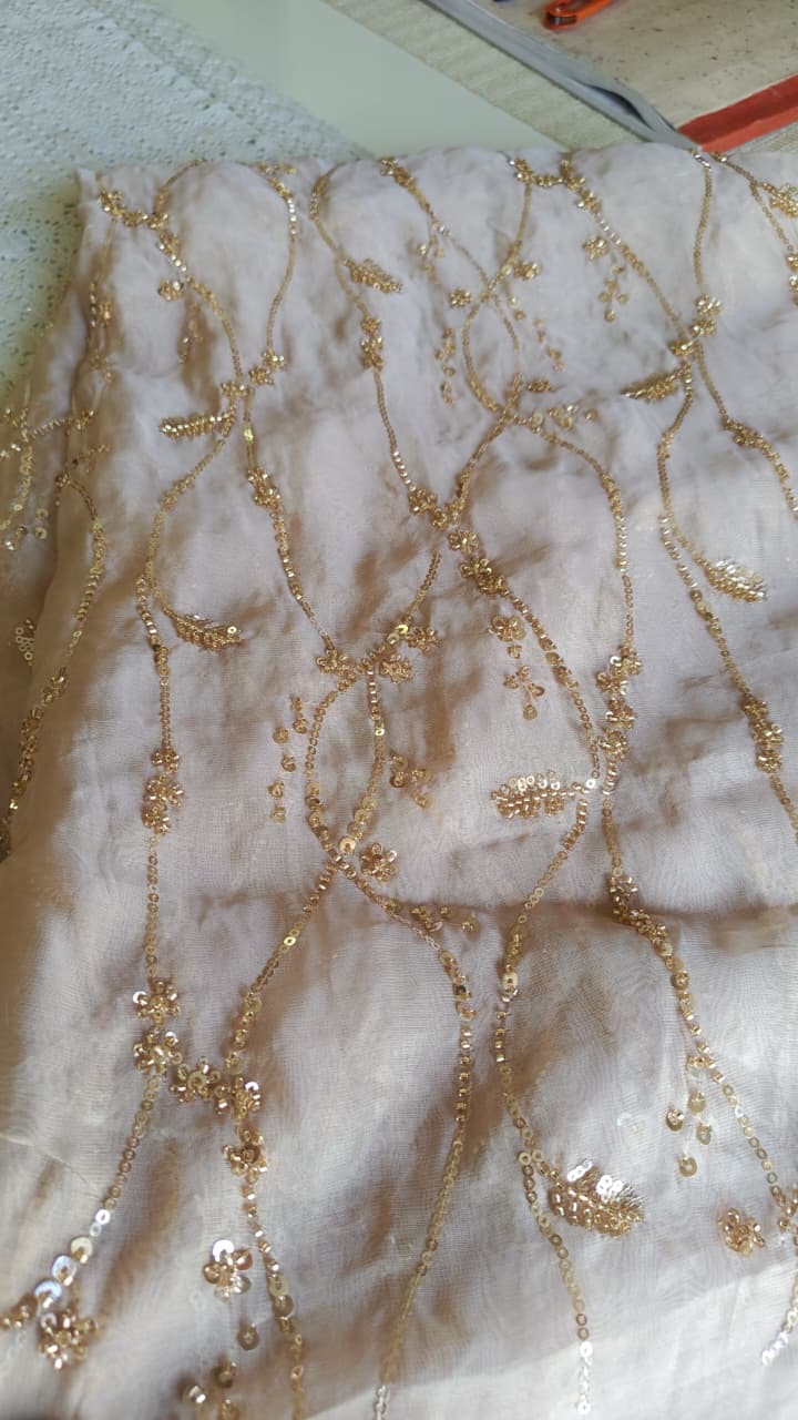 Fine branching vines and floral shapes traced across pale fabric.
