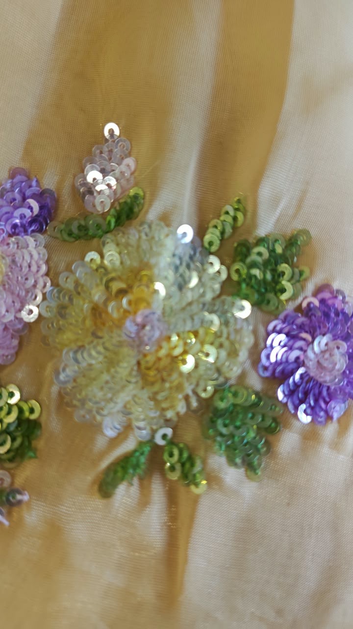A small cluster of purple, green and white floral details on yellow.