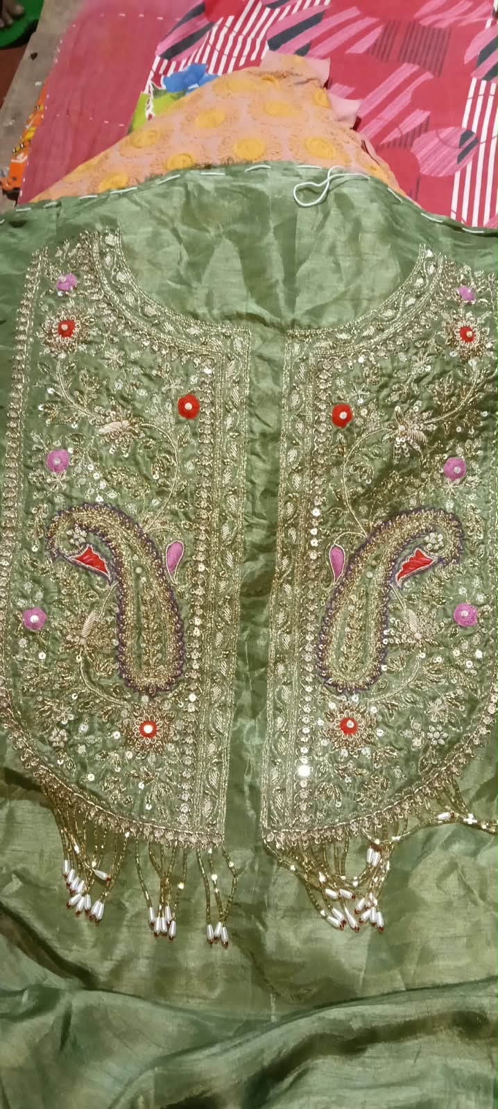 A sage green garment panel with symmetrical floral neckline detailing.